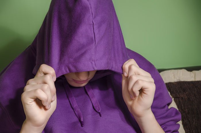 teenager in bright purple hooded sweatshirt covering head