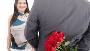 man hiding red rose bouquet behind his back