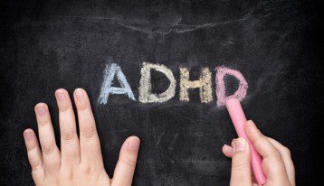 ADHD written in colored chalk on black chalkboard
