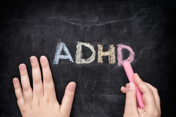 ADHD written in colored chalk on black chalkboard
