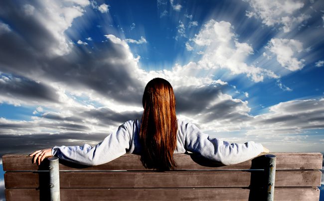 red haired woman on park bench facing away from camera