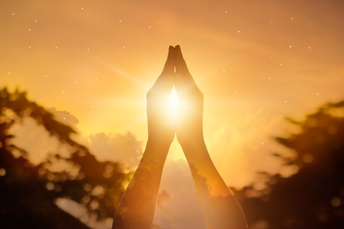 hands raised in prayer at sunset