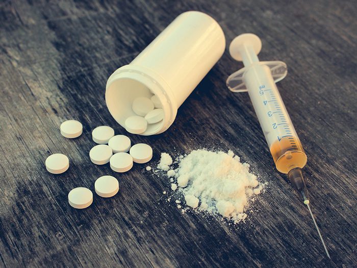 white pills spilling out of bottle - white powder - syringe full of drugs