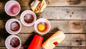 solo cups with alcohol and beer cans on wood table