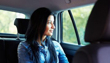 woman in back seat of car smiling looking out window