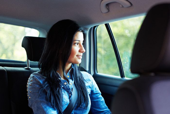 woman in back seat of car smiling looking out window