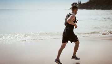 man in black shorts and shirt running on beach - physical