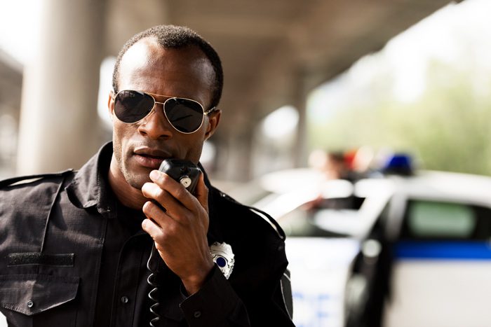 High-Risk Professions, African American male police officer using CB radio - work