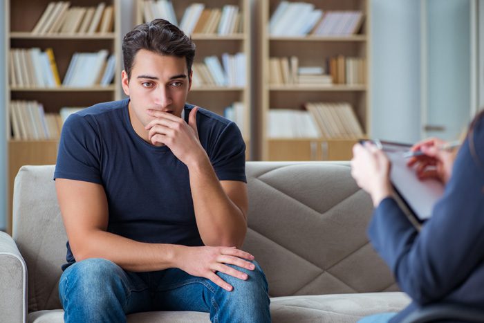 young man in therapy session with counselor - CBT