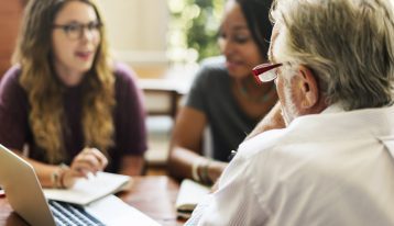 manage anxiety and frustration in college, two female students meeting with older male professor - students