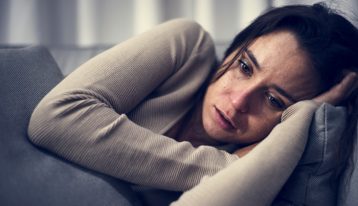 Co-Occurring Disorders, Most commonly, individuals with substance use disorders suffer from anxiety and mood-related disorders, sad young woman on couch closeup - addiction causes