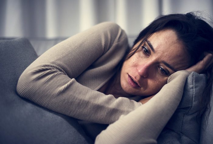 Co-Occurring Disorders, Most commonly, individuals with substance use disorders suffer from anxiety and mood-related disorders, sad young woman on couch closeup - addiction causes