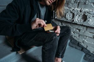 long haired man cutting lines of cocaine on a credit card - cocaine addiction