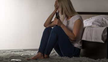 Girl sitting on floor with alcohol bottle - College