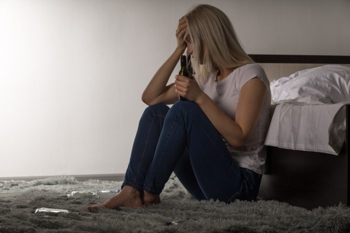 Girl sitting on floor with alcohol bottle - College