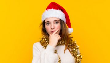 young woman in a Santa hat with questioning body language - holidays and addiction