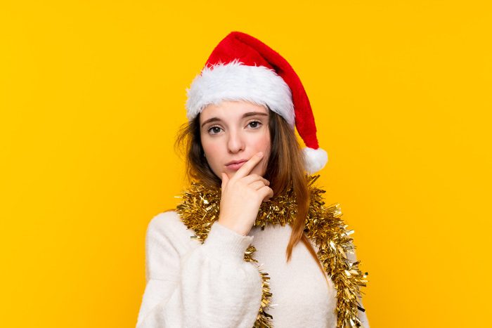 young woman in a Santa hat with questioning body language - holidays and addiction