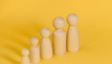 wooden pegs representing family members against yellow background - family systems therapy