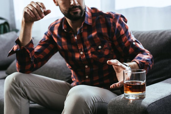 Addiction to Central Nervous System Depressants, cropped shot of man reaching for a tumbler of liquor - depressants