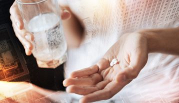 woman's hand with 3 small white pills and a glass of water in the other hand - oxymorphone