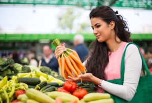 Nutrition and Exercise in Addiction Recovery, Nutrition and Addiction Recovery, Nutrition, beautiful Latina woman holding a bunch of carrots in the produce section of a grocery store - exercise