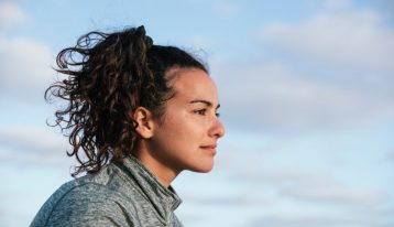 pretty brunette young woman looking forward with the sky behind her - alumni support