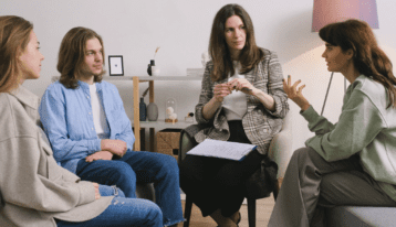 A group of people talking to a therapist.