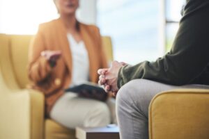 Close-up of a therapy or counseling session, showing two people seated across from each other, with one person speaking and the other listening attentively.