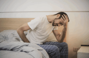 A man sitting in bed looking sick.