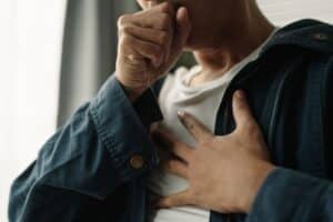 Ranch at Dove Tree - What Are the Health Risks of Commonly Misused Substances. An individual is pictured coughing with his hand to his chest.,